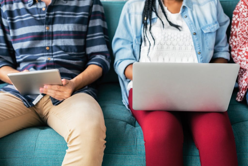 Two bodies using a laptop and tablet on their laps