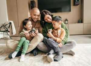 family sitting on living room floor with kids on their lap