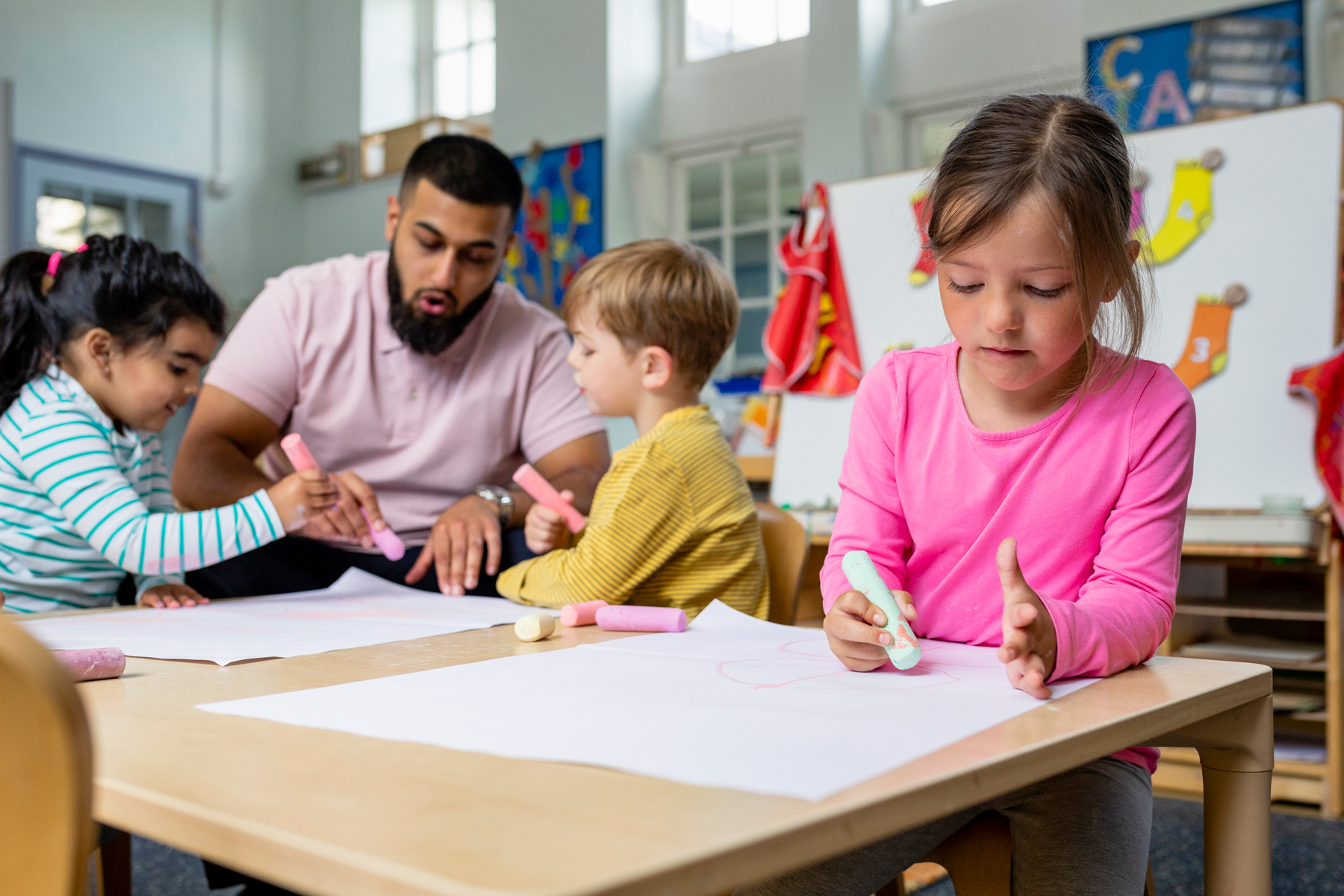 Teacher with students using big chalk sticks