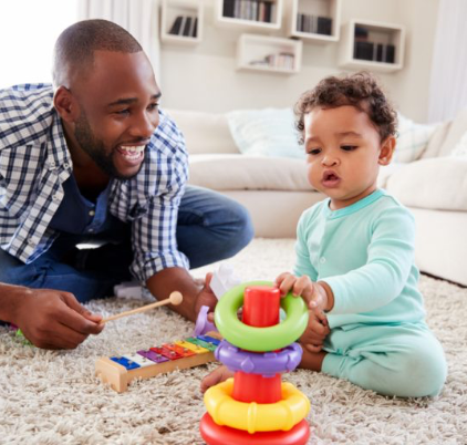 Child and father play on the floor of living room. 